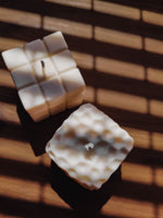 bougie cube sur une table pour décorer son intérieur. bougie déco cube en cire naturelle.